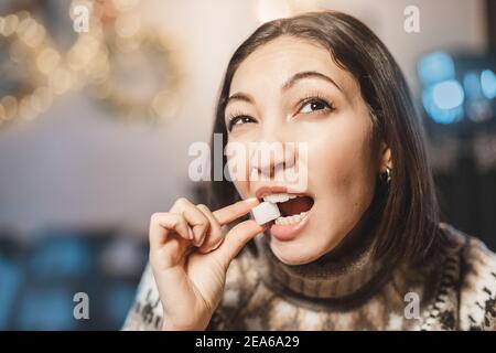 La femme asiatique goûte et grignote un morceau de sucre blanc raffiné. Le concept de consommation excessive de glucides rapides et de santé dentaire Banque D'Images