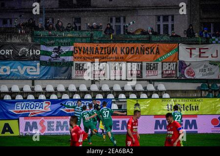 Les fans, debout sur des échelles derrière la clôture, regardent un match de la première division tchèque entre Bohemians Prague et le FC Zbrojovka Brno à Prague, République Tchèque, le samedi 6 février 2021. Parmi les mesures restrictives qui limitent le nombre de fans de football à assister au match, les fans recherchent des moyens novateurs de regarder le match pendant la pandémie du coronavirus. (CTK photo/Roman Vondrous) Banque D'Images