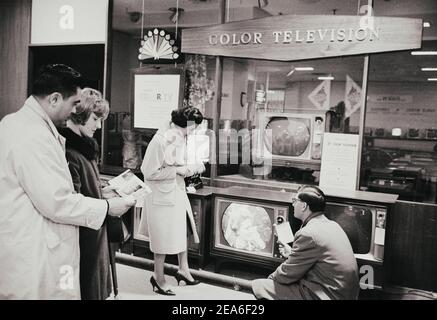 Photo vintage de shoppwrs avant la boutique de fenêtre avec de nouveaux modèles de télévision couleur. ÉTATS-UNIS. 16 mars 1965. Banque D'Images