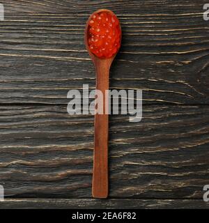 Cuillère avec caviar rouge sur fond en bois, vue de dessus Banque D'Images