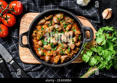 Ragoût de cœurs de poulet et de légumes avec du persil frais. Arrière-plan noir. Vue de dessus Banque D'Images