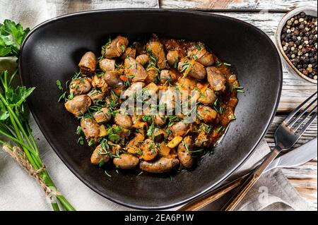 Ragoût de cœurs de poulet et de légumes avec du persil frais. Arrière-plan blanc. Vue de dessus Banque D'Images