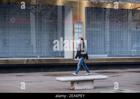 Les personnes qui portent un masque facial se promondent devant des boutiques fermées et fermées le long du quartier commerçant d'Oxford Street, qui est en grande partie vide de clients alors que le confinement national du coronavirus trois se poursuit le 28 janvier 2021 à Londres, au Royaume-Uni. Suite à la flambée de cas durant l'hiver, y compris une nouvelle variante britannique de Covid-19, ce confinement national conseille à tous les citoyens de suivre le message de rester à la maison, de protéger le NHS et de sauver des vies. Banque D'Images