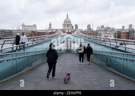 Femme marchant son chien au-dessus d'un très calme Millennium Bridge vers la cathédrale St Pauls alors que le confinement national du coronavirus trois se poursuit le 28 janvier 2021 à Londres, Royaume-Uni. Suite à la flambée de cas durant l'hiver, y compris une nouvelle variante britannique de Covid-19, ce confinement national conseille à tous les citoyens de suivre le message de rester à la maison, de protéger le NHS et de sauver des vies. Banque D'Images