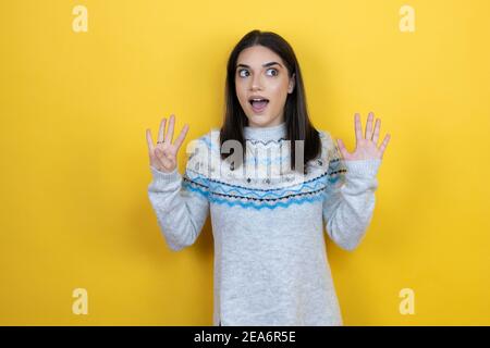 Jeune femme caucasienne portant un chandail décontracté sur fond jaune montrant et en pointant vers le haut avec les doigts numéro neuf tout en souriant confiant et heureux Banque D'Images