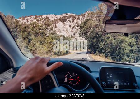 Le conducteur garde fermement les mains sur le volant sur la route sinueuse de montagne. Le concept de la sécurité routière et des déplacements personnels Banque D'Images