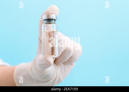 Covid 19 coronavirus vaccin en flacon de verre, médicament liquide dans la main du médecin dans le gant. Simulation de traitement par injections de vaccination. Covid Banque D'Images