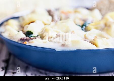 Gros plan extrême résumé de la soupe Tortellini avec saucisses italiennes, épinards et carottes. Mise au point sélective avec arrière-plan flou. Banque D'Images