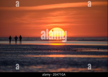 Personnes au coucher du soleil dans les wadden à Cuxhaven au coucher du soleil - Menschen im Watt von Cuxhaven im Sonnenuntergang Banque D'Images