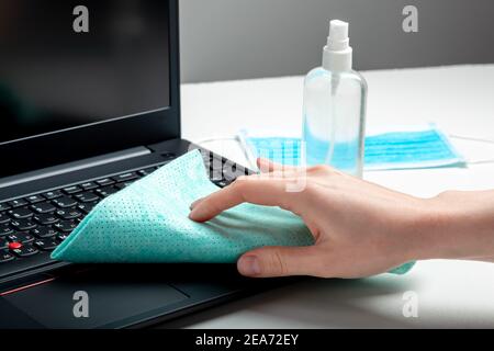 Mains de femmes désinfection du clavier de l'ordinateur portable à l'aide d'un spray désinfectant, d'un assainisseur d'alcool, de lingettes désinfectantes humides. Femme nettoyant le clavier. Nouvelle normale Banque D'Images