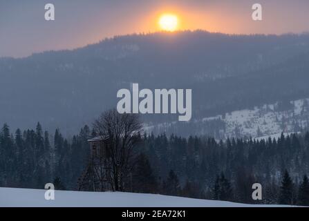 tour de chasse dans les paysages de montagne d'hiver au lever du soleil Banque D'Images