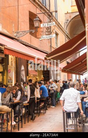 Les personnes qui dînent à l'extérieur au restaurant et bar italien Simoni dans les rues étroites de Bologne Italie Banque D'Images