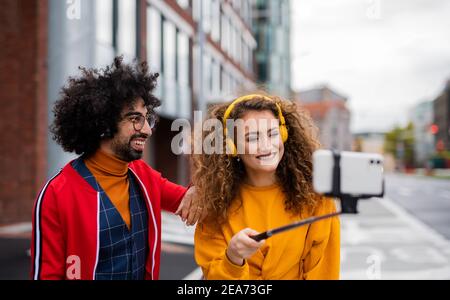 Jeune couple avec smartphone pour la vidéo des médias sociaux en plein air dans la rue. Banque D'Images