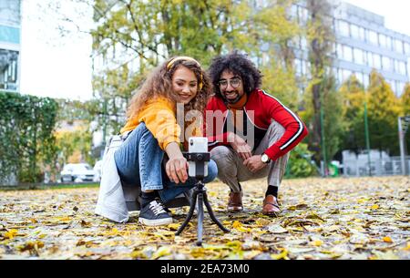 Un jeune couple avec un smartphone fait de la vidéo pour les médias sociaux en plein air dans le parc. Banque D'Images