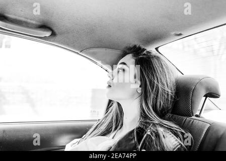 Fille dans le siège arrière de la voiture. Brunette en voiture. Belle jeune fille manèges dans un taxi Banque D'Images