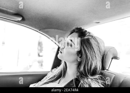 Fille dans le siège arrière de la voiture. Belle jeune fille manèges dans un taxi dans le siège arrière Banque D'Images