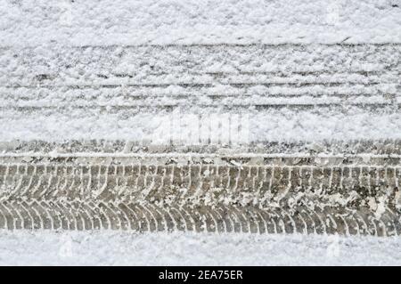 Différence sur une route enneigée entre un pneu standard et un pneu à neige avec chenilles Banque D'Images