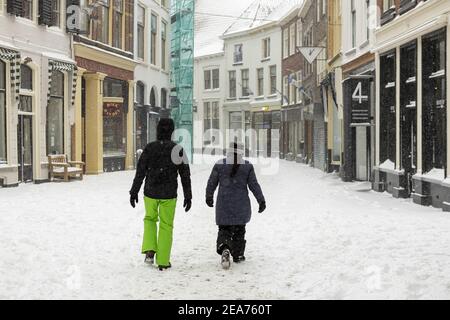 ZUTPHEN, PAYS-BAS - 07 févr. 2021 : couple marchant dans les rues du centre-ville historique hollandais après une tempête de neige avec des chemins blancs Banque D'Images