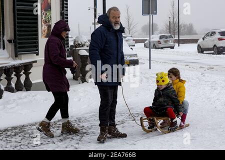 ZUTPHEN, PAYS-BAS - 07 février 2021 : grand-père et petites-filles avec traîneau dans les rues du boulevard de la ville néerlandaise après la chute de neige avec chemin blanc Banque D'Images
