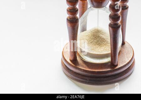 Gros plan sur un sablier vintage en bois. Sable passant à travers les ampoules en verre d'un sablier mesurant le temps de passage comme il compte à un délai Banque D'Images