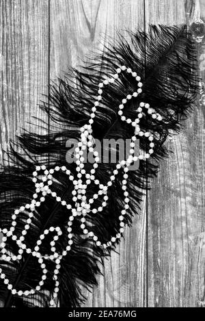 Image monochrome d'une chaîne de perles et de plumes noires surface en bois Banque D'Images