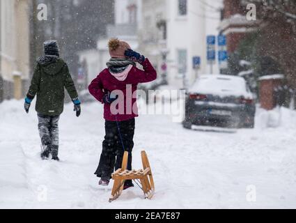 Bad Oeynhausen, Allemagne. 08 février 2021. Deux enfants sont en route avec un toboggan. Après le début de l'hiver, le grand froid arrive en Rhénanie-du-Nord-Westphalie. Selon les prévisions du service météorologique allemand à partir de lundi, les températures ne s'élèveront pas au-dessus de zéro degré même pendant la journée jusqu'au week-end (13./14.02.2021). Crédit : Lino Mirgeler/dpa/Alay Live News Banque D'Images