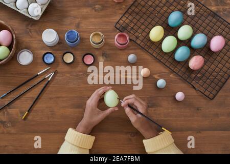 Vue de dessus arrière-plan des mains d'enfant peinture pastel oeufs de Pâques sur table en bois, bricolage décorations de Pâques, espace de copie Banque D'Images