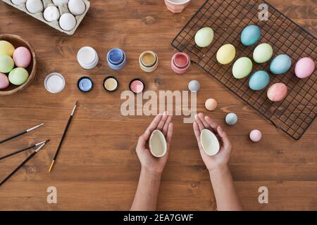 Vue de dessus arrière-plan des mains d'enfant peinture pastel oeufs de Pâques sur table en bois, bricolage décorations de Pâques, espace de copie Banque D'Images