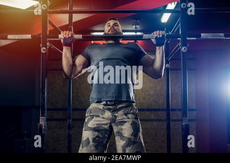 Homme barbu fortement concentré qui se tient au bar de la salle de gym. Banque D'Images