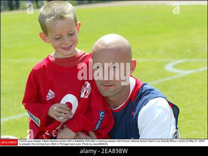 Fabien Barthez, gardien de but français, pose avec un enfant handicapé après une session de formation avec l'équipe nationale française de football à la Grande Motte-France le 27 mai 2004 pour préparer l'Euro 2004 à venir au Portugal en juin prochain. Photo de Java/ABACA. Banque D'Images