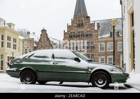ZUTPHEN, PAYS-BAS - 07 février 2021 : voiture d'époque recouverte de neige avec façade médiévale en arrière-plan Banque D'Images