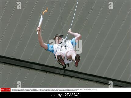 David Douillet, ancien judoka olympique, porte la flamme olympique au cours du jour 21 du Relais de la flamme olympique D'ATHÈNES 2004 le 25 juin 2004 au Stade de France à Saint-Denis près de Paris-France. La flamme olympique se rend dans 34 villes de 27 pays en route vers les Jeux Olympiques d'Athènes en 2004. Photo de Mousse-Lamperti-Gorassini-Klein/ABACA. Banque D'Images