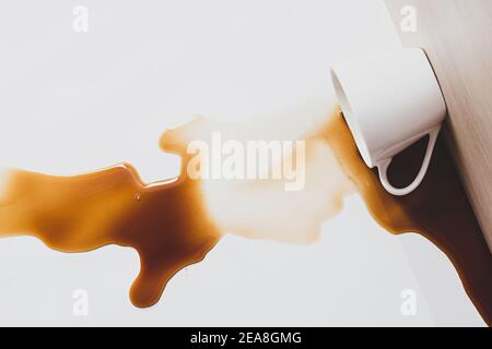 Tasse de café renversée. Tache de café noir déversée d'une tasse blanche sur un fond clair Banque D'Images