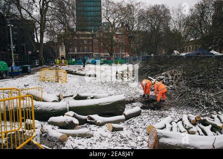 Londres, Royaume-Uni. Le treize jour des expulsions d'Euston Square, les travailleurs de HS2 continuent de creuser dans la neige à Euston Square, Londres, Royaume-Uni. 8 février 2021. Les billes et les branches des arbres de plan abattus sont dispersées autour. Le camp anti HS2 continue d'être libéré (afin de créer une aire de stationnement temporaire) par les Bailiffs (de l'équipe nationale d'application de la loi, NET, une filiale du High court Enforcement Group) à Euston Station. Tous les manifestants au-dessus du sol ont été dégagés et ils commencent maintenant à creuser autour des tunnels. Denise Laura Baker/Alay Live News Banque D'Images