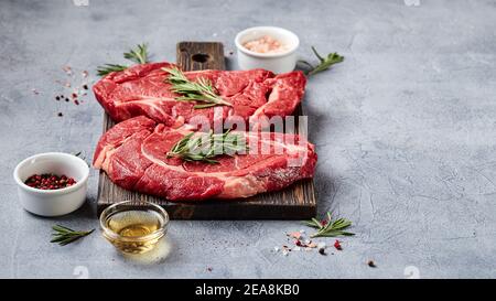 Deux steaks de bœuf Black Angus de viande fraîche brute, Rib Eye, Denver, sur planche à découper en bois. Place pour le texte. Banque D'Images