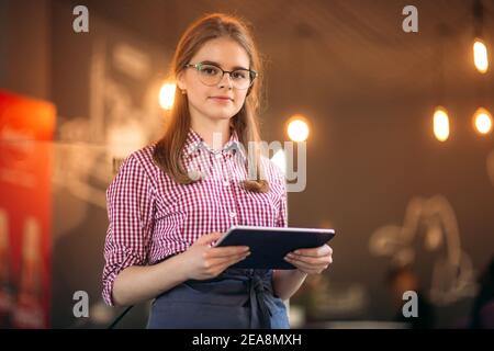 Serveuse jeune et attrayante utilisant une tablette Banque D'Images
