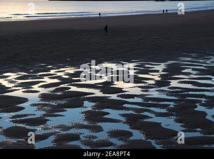 Personnes sur la plage à marée basse avec un modèle de sable et d'eau de mer avec le ciel reflété dans l'eau tôt le matin Santander Cantabria Espagne Banque D'Images