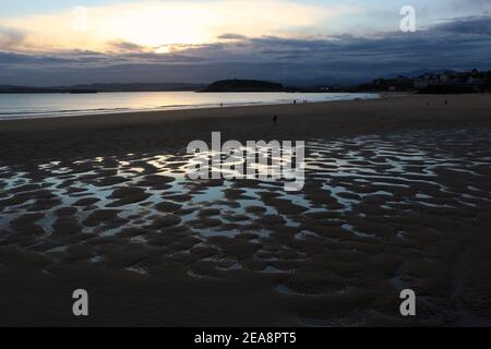 Personnes sur la plage à marée basse avec un modèle de sable et d'eau de mer avec le ciel reflété dans l'eau tôt le matin Santander Cantabria Espagne Banque D'Images