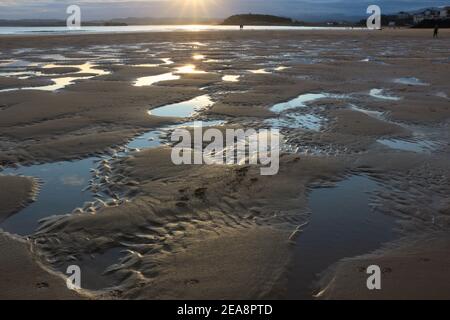 Personnes sur la plage à marée basse avec un modèle de sable et d'eau de mer avec le ciel reflété dans l'eau tôt le matin Santander Cantabria Espagne hiver Banque D'Images