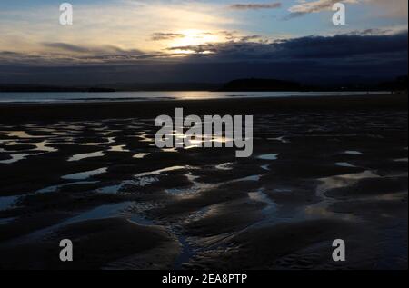 Personnes sur la plage à marée basse avec un modèle de sable et d'eau de mer avec le ciel reflété dans l'eau tôt le matin Santander Cantabria Espagne Banque D'Images