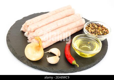 Saucisses de viande crue pour la friture avec des épices sur fond noir. Studio photo Banque D'Images