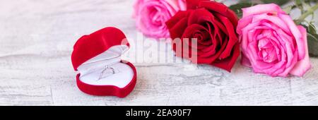 Bannière avec anneau de mariage à l'intérieur de la boîte en velours rouge pour l'anneau d'engagement à côté du bouquet de roses. Cadeau romantique pour la Saint-Valentin. Proposition de mariage conc Banque D'Images