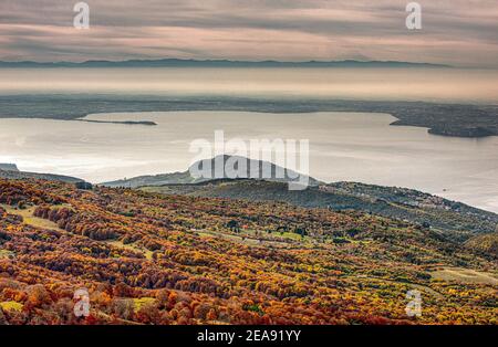 Italie Veneto Monte Baldo - Salendo verso il Costabella si risale la dorsale della montagna su terreno erboso e aperto che offre un panorama eccellante sul lago di Garda. più à basso i boschi accesi dal feuillage|Italie Veneto Monte Baldo - en allant vers le Costabella vous montez sur la crête de la montagne sur un sol herbacé et ouvert qui offre une excellente vue sur le lac de Garde. Plus bas dans les bois éclairés par le feuillage. Banque D'Images