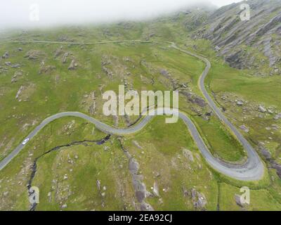 Vue aérienne d'une voiture longeant la route venteuse de la région irlandaise connue sous le nom de Healy Pass (R574) situé dans le comté de Cork, en Irlande. Banque D'Images