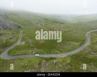 Vue aérienne d'une voiture longeant la route venteuse de la région irlandaise connue sous le nom de Healy Pass (R574) situé dans le comté de Cork, en Irlande. Banque D'Images