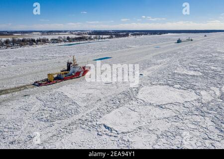 Roberts Landing, Michigan, États-Unis. 7 février 2021. Le brise-glace de la Garde côtière canadienne Samuel Risley (rouge) et le garde-côte américain Bristol Bay (petit navire au loin) travaillent ensemble pour aider le Challenger St Marys, un cargo des Grands Lacs, à naviguer sur la rivière glacée St. clair. Le froid amer a entraîné des embâcles sur la rivière et des inondations dans les communautés riveraines. La rivière Sainte-Claire est la frontière entre les États-Unis et le Canada; elle draine les Grands Lacs supérieurs vers le lac Sainte-Claire et le lac Érié. Crédit : Jim West/Alay Live News Banque D'Images