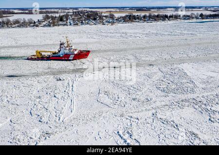 Roberts Landing, Michigan, États-Unis. 7 février 2021. Le brise-glace de la Garde côtière canadienne Samuel Risley brise la glace sur la rivière St. clair. Le froid amer a entraîné des embâcles sur la rivière et des inondations dans les communautés riveraines. La rivière Sainte-Claire est la frontière entre les États-Unis et le Canada; elle draine les Grands Lacs supérieurs vers le lac Sainte-Claire et le lac Érié. Crédit : Jim West/Alay Live News Banque D'Images