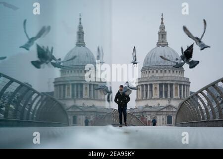 Un homme traverse le Millennium Bridge de Londres pendant une douche à neige, tandis que la neige est sur le point de perturber le sud-est de l'Angleterre et l'est Anglia, car des vents amèrement froids continuent d'attraper une grande partie de la nation. Date de la photo: Lundi 8 février 2021. Banque D'Images