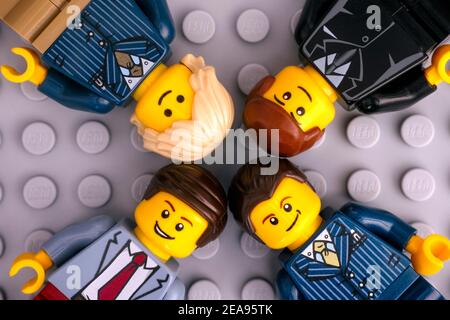 Tambov, Fédération de Russie - 17 janvier 2021 quatre hommes d'affaires Lego se minifigurent sur fond de plaque de base grise. Banque D'Images