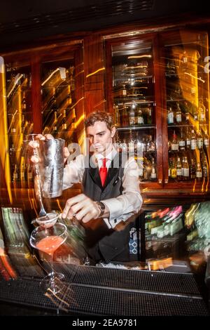 Une machine à cocktails qui travaille derrière un bar animé de l'hôtel et qui prépare un verre avec un shaker. Banque D'Images